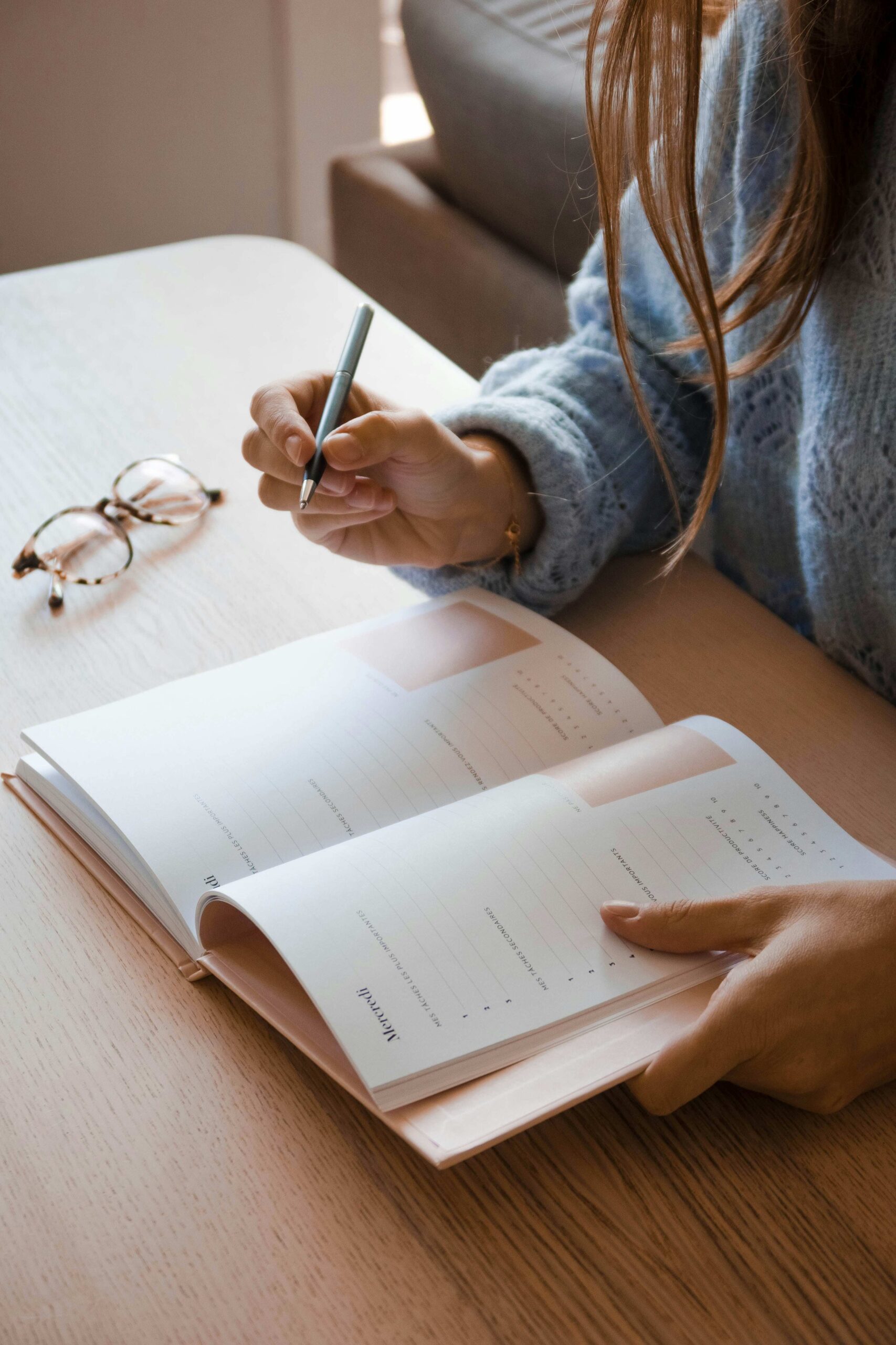 Person writing in a minimalist planner, reflecting on sustainable business models that prioritize personal energy and alignment.
