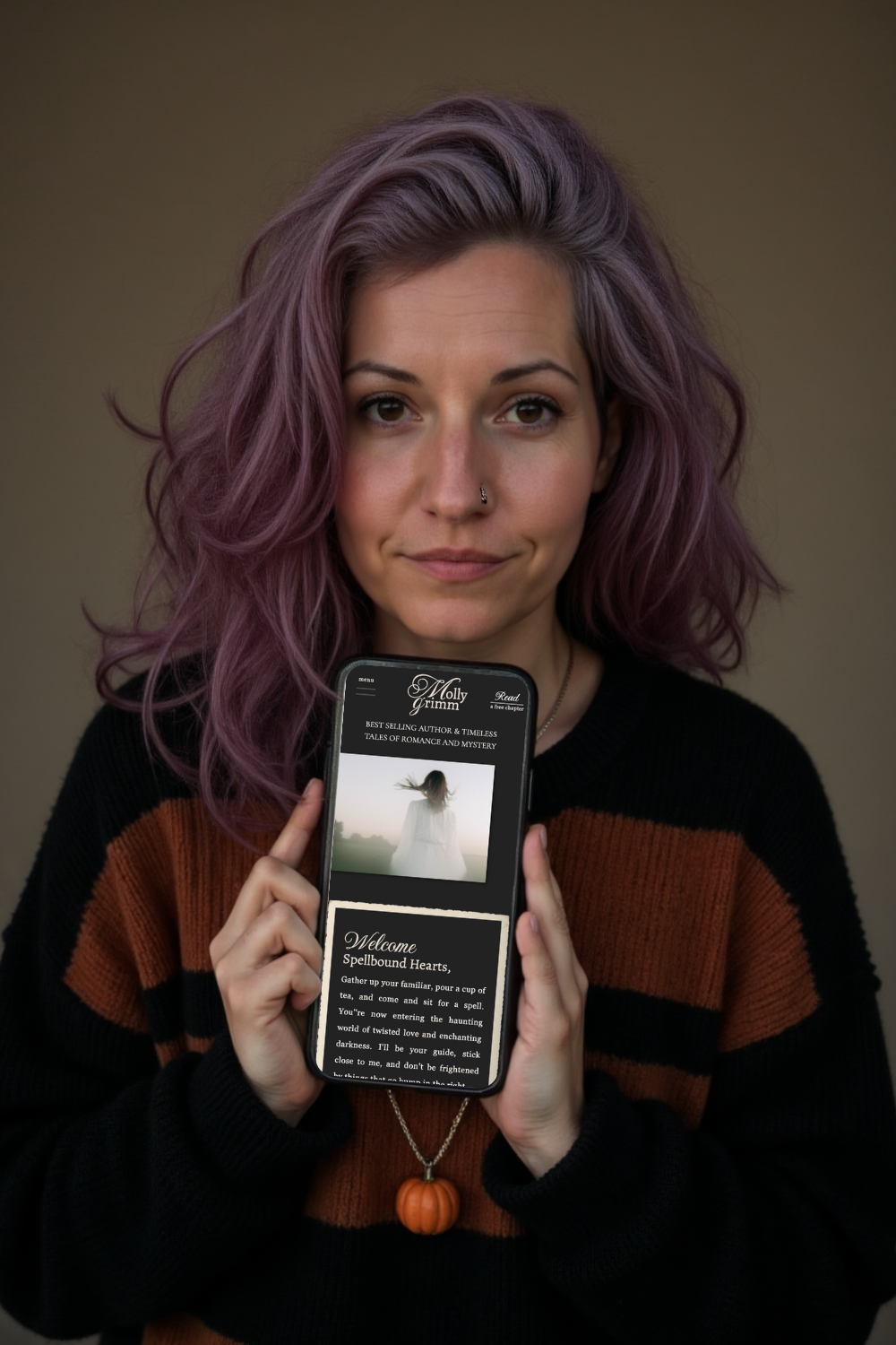 Jamie Sabot holding a phone displaying the Dark Academia Showit website template mockup she designed.